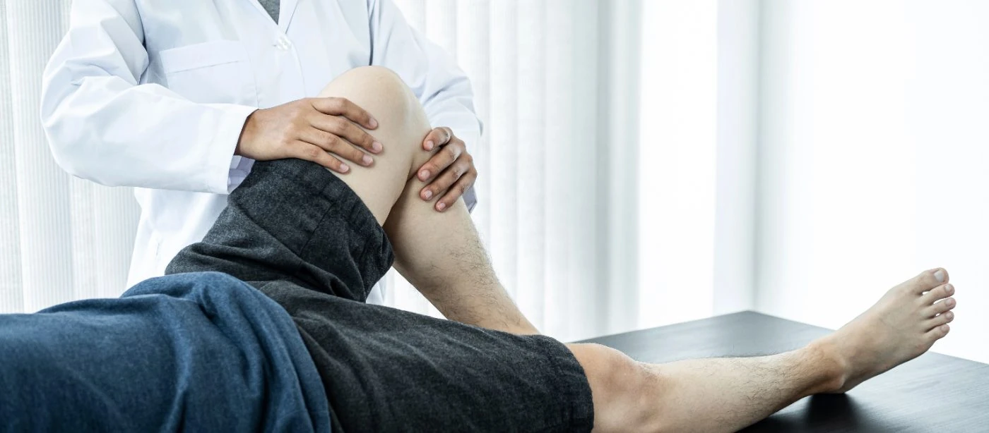 Doctor examining a patient's bent knee during a clinical evaluation for knee pain
