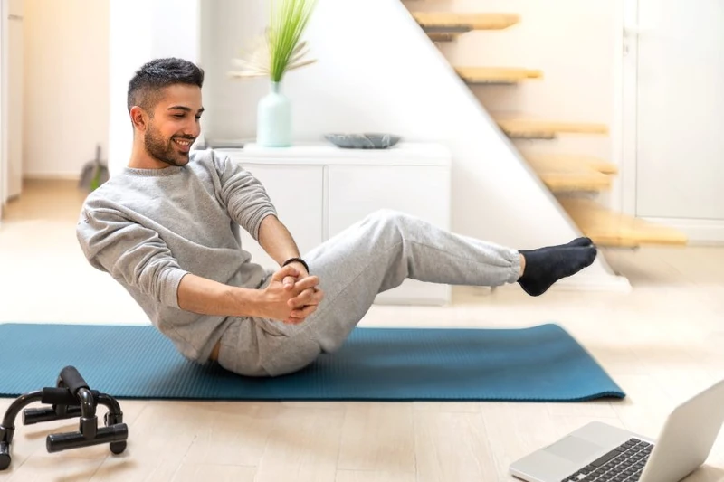 Man doing a seated balance exercise on an exercise mat at home