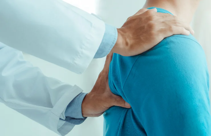 Doctor's hand resting on a patient's shoulder during an examination